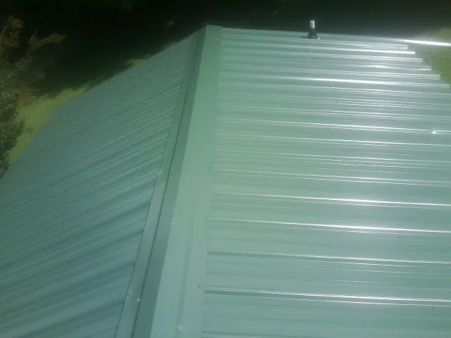 New green metal panels meeting at the ridge of a roof — Flat Roof Repair work by our crew in Monterey