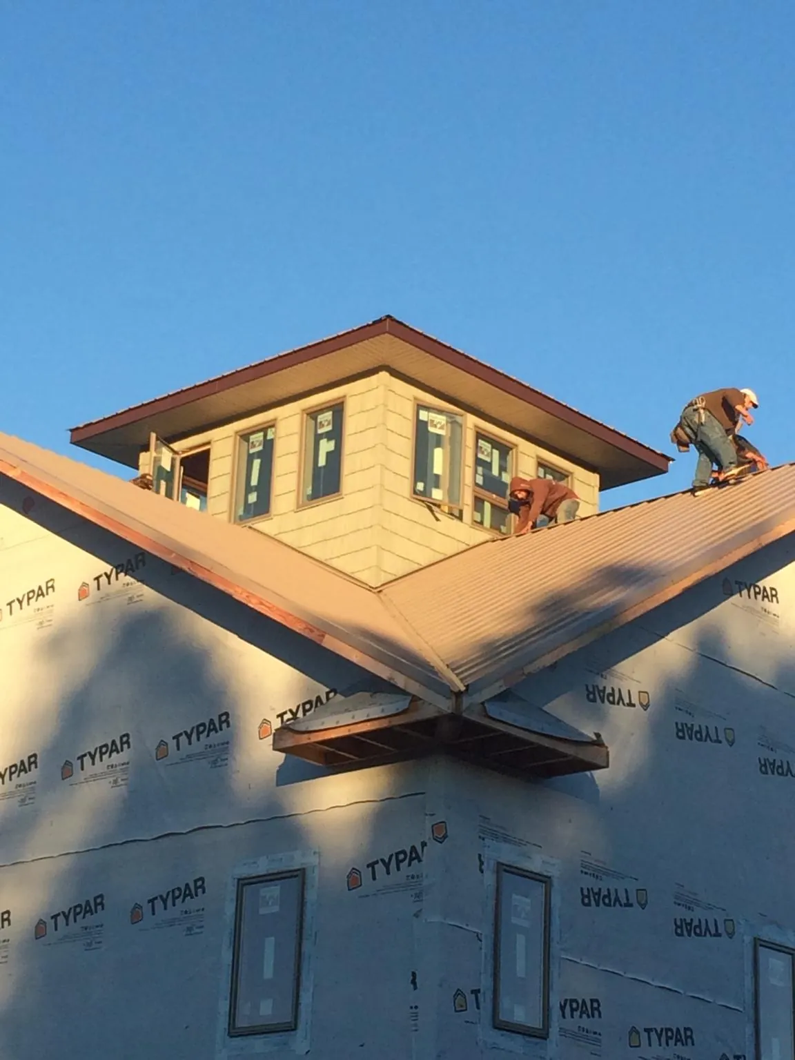 Roofers working around a rooftop cupola on a new metal roof at sunset — Roof Waterproofing in Monterey by Roofing Brothers